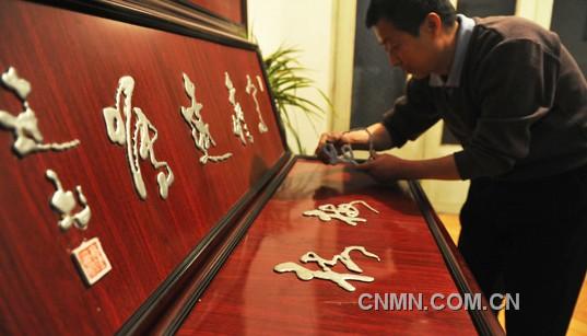 图为高建书展示金属液体书写的梅、花字。耳太