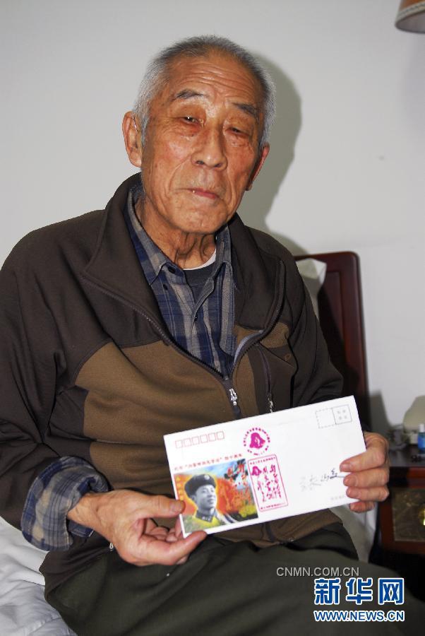 八旬老摄影家张峻为来访者在雷锋纪念封上签名留念（2012年2月28日摄）。