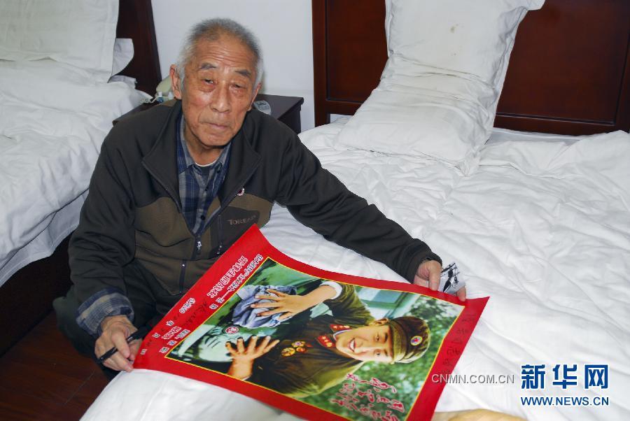 八旬老摄影家张峻为来访者在雷锋宣传画上签名留念（2012年2月28日摄）。