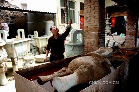 河南省洛阳烟涧村的青铜器高仿作坊中，一件半成品被浸泡进电解水中，进入做旧工序