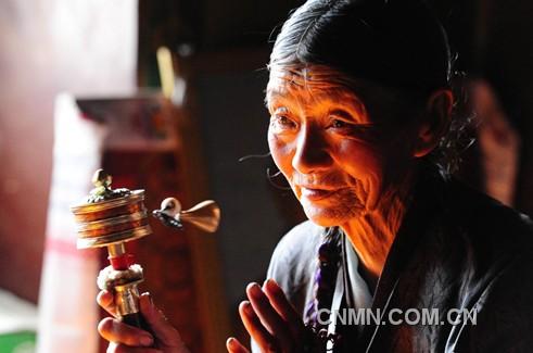 一名藏族老人在西藏自治区山南地区昌珠寺手摇转经筒，虔诚地诵念佛经