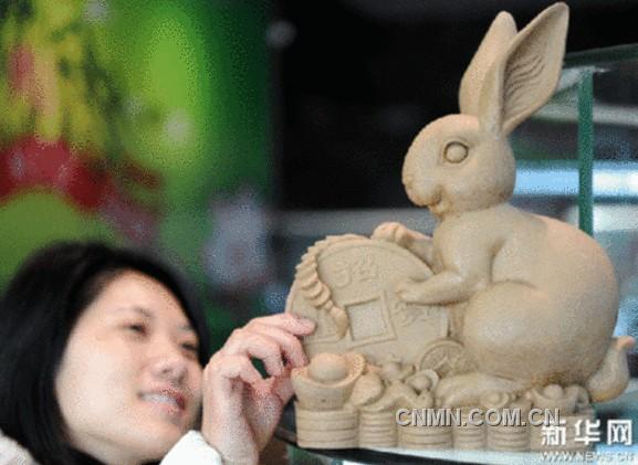 定南县一家金属工艺公司的员工展示为兔年新春制作的钨砂作品“玉兔迎春”。